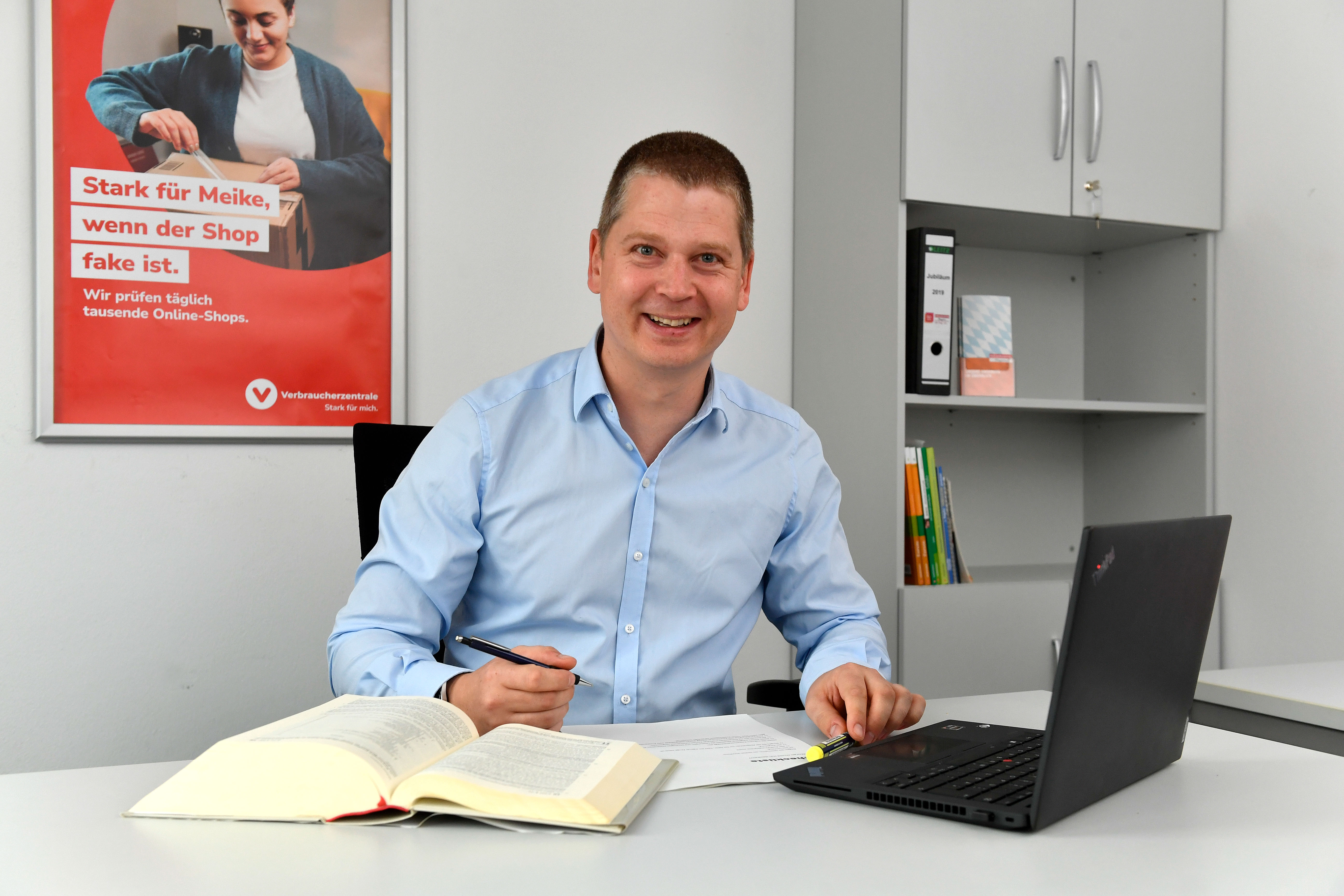 Ein Jurist blickt in die Kamera. Neben ihm ein Gesetzesbruch und ein Laptop