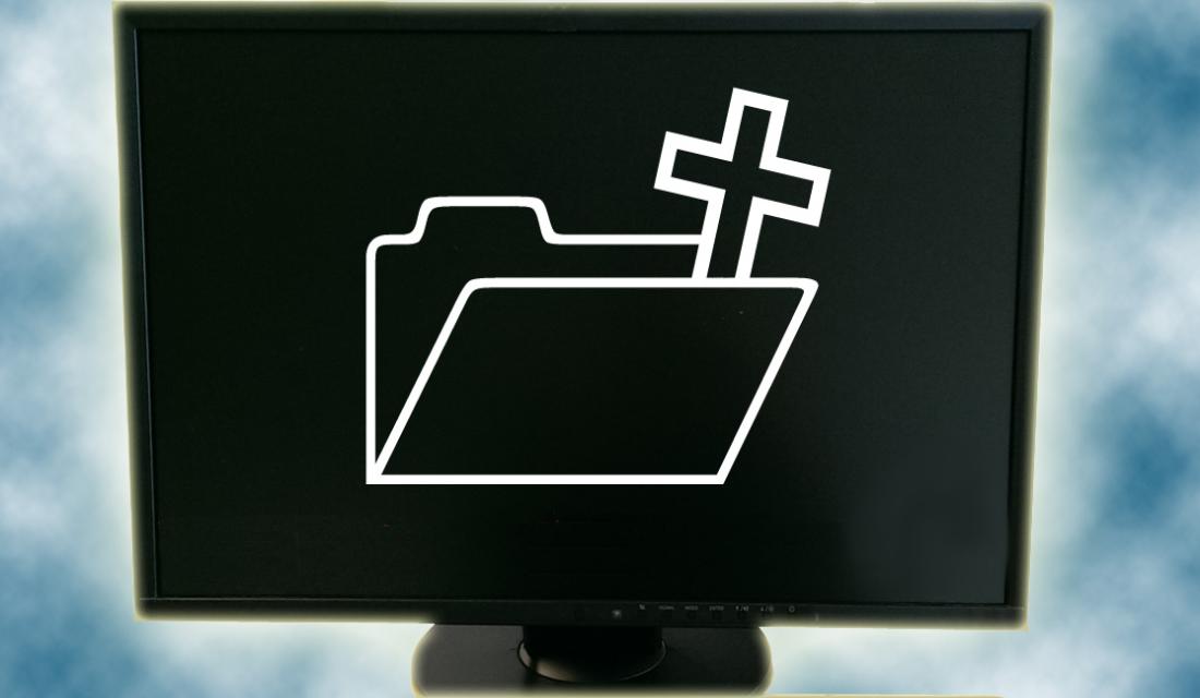 Ein schwarzer PC-Monitor vor einem Wolkenhintergrund zeigt einen aufgeklappten Ordner und ein Christus-Kreuz.