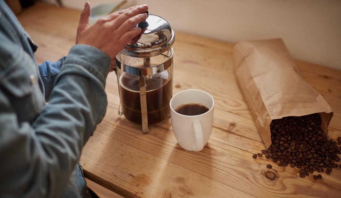 Jemand bereitet Kaffee in einer French Press zu