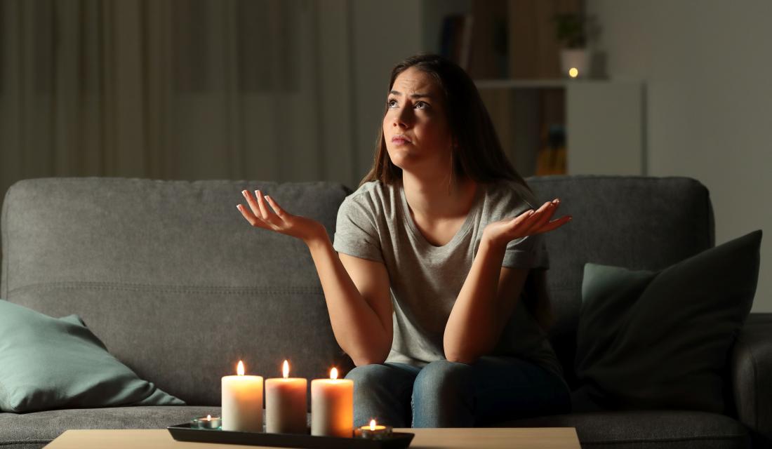 Eine junge Frau sitzt wegen einer Stromsperre bei Kerzenlicht im Dunkeln 