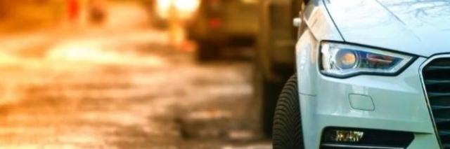 Foto eines an einer Straße geparkten Autos von vorne im Anschnitt