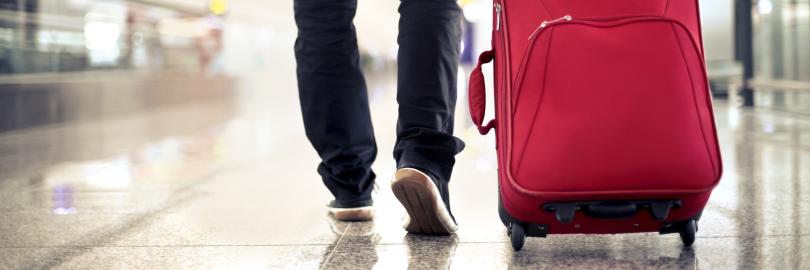 Mann mit Rollkoffer am Flughafen