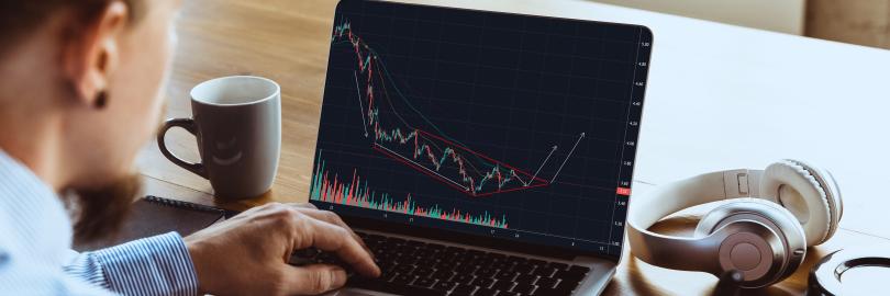 Ein Mann sitzt am Laptop und schaut sich die Aktienkurse an.