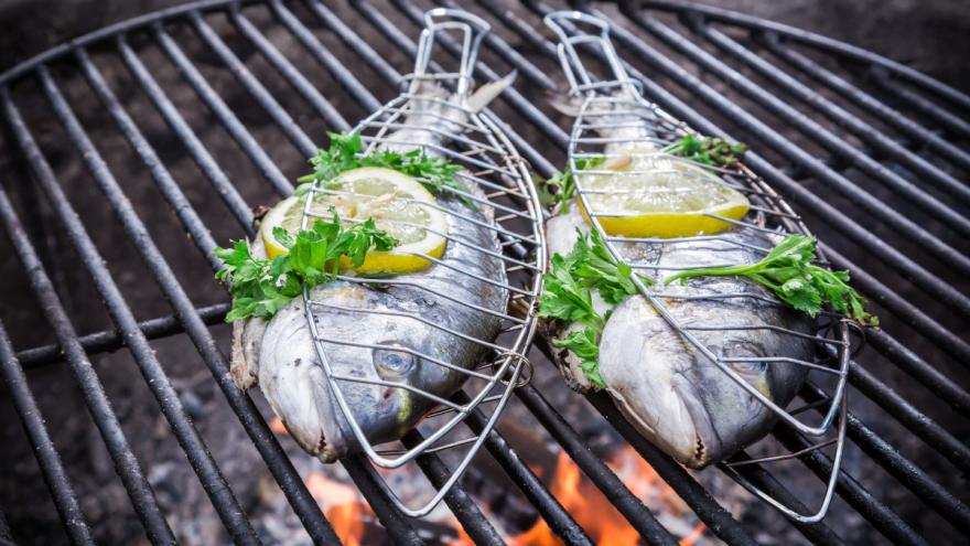 Fische in Grillzangen auf dem Grill