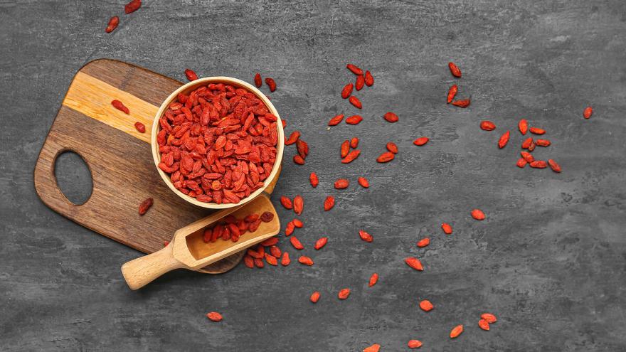 Gojibeeren in einer Schüssel und verstreut auf einem Brett und dem Tisch