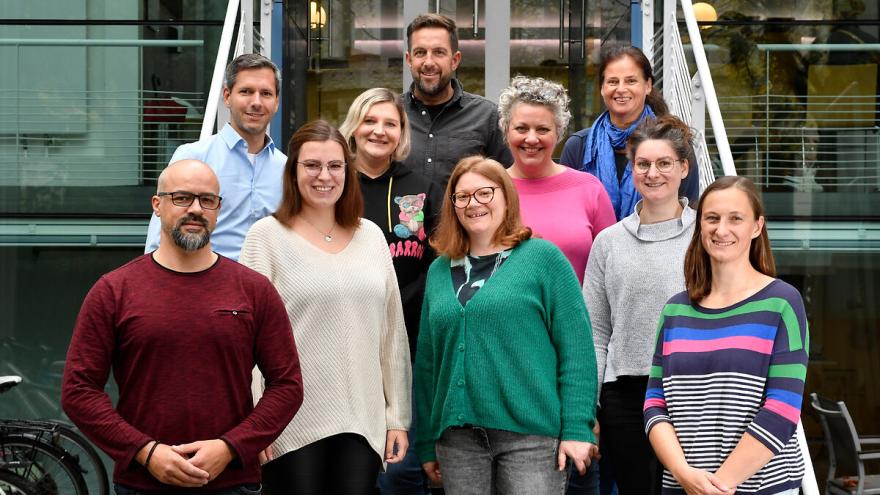 Das Team aus 10 Personen des Projekts VLJM steht auf einer Treppe und bilckt in die Kamera.