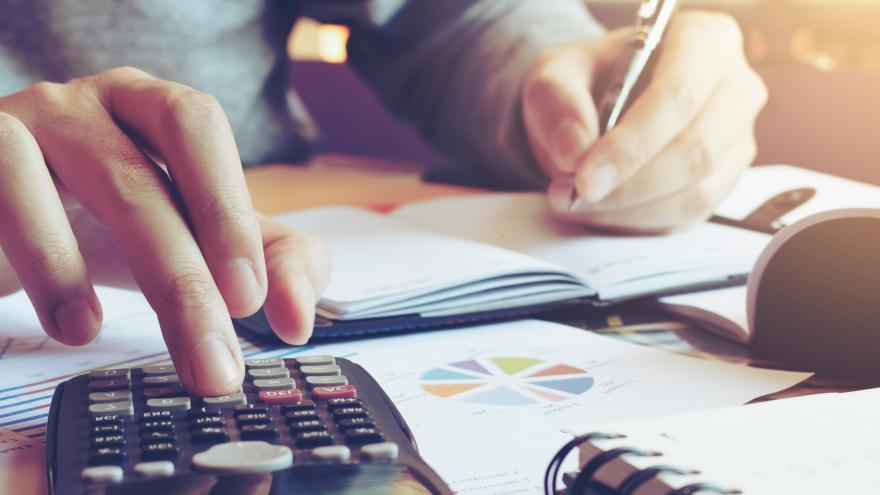 Hände mit Stift und Taschenrechner