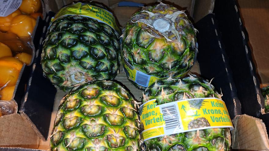 Vier Ananas ohne Krone liegen in einer Obstkiste.