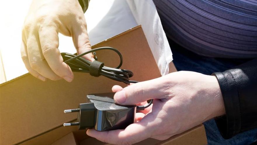 Hände packen aus einer Schachtel ein Kabel aus