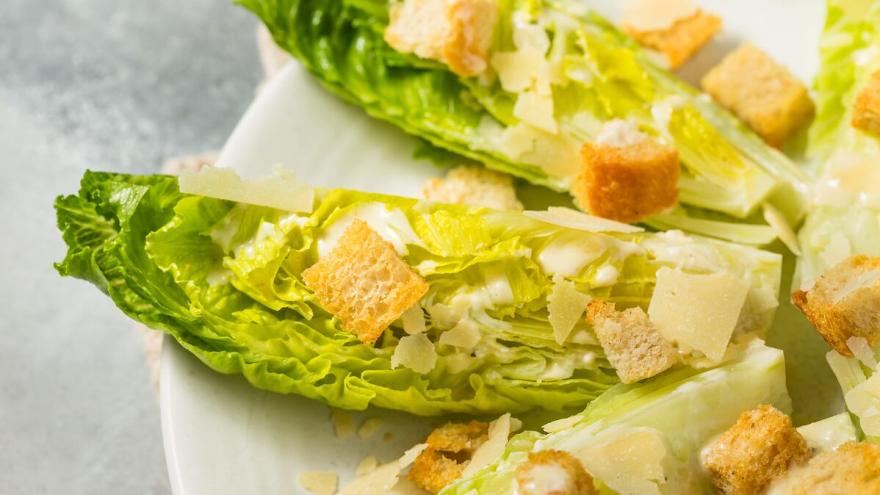 Romana-Salatblätter mit Croûtons auf einem weißen Teller.