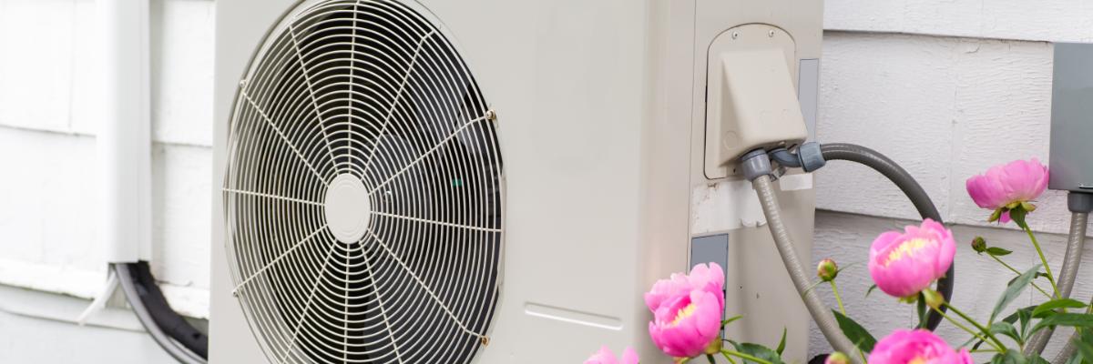 Eine Wärmepumpe hängt außen an einer Hauswand.