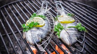Fische in Grillzangen auf dem Grill