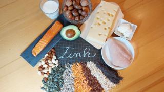 Verschiedene Lebensmittel, die Zink enthalten, sind um eine Tafel gruppiert, auf der das Wort Zink steht.