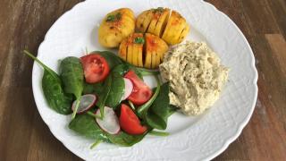 Ein Teller mit Akkordeonkartoffeln, Hummus und Salatbeilage