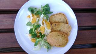 Ein Teller mit Linsenpfannkuchen und Feldsalat mit Orangen