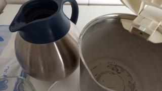 Neben einer Teekanne steht ein geöffneter Wasserkocher. In ihm sieht man deutliche Kalkspuren.