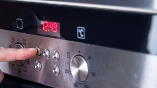 Ein Finger tippt auf einen Schalter im Bedienbereich eines Backofens