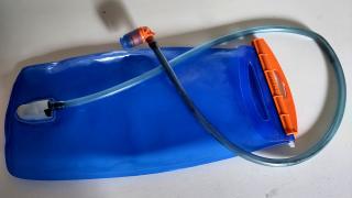 Eine blaue Trinkblase mit Schlauch liegt auf einem Tisch.