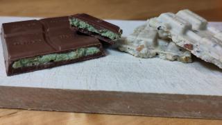 Stücke von Vollmilch- und weißer Dubaischokolade auf einem Schneidebrett