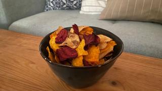 Eine Schüssel mit Gemüsechips steht auf einem Couchtisch.