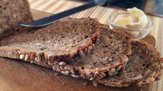 Drei aufgeschnittene Scheiben Brot liegen auf einem Brett.