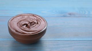 Eine Schüssel Schokopudding steht auf einem blauen Holztisch