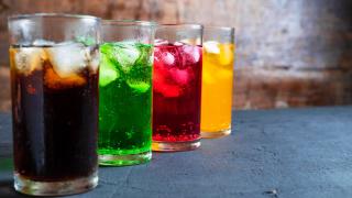 Bunte Getränke mit Eiswürfeln in hohen Gläsern.