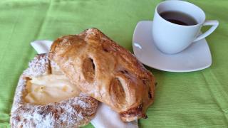 Zwei Gebäckstücke liegen auf einer Serviette, daneben eine Tasse Tee.