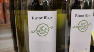 Zwei Flaschen Pinot Blanc mit der Aufschrift "Entalkoholisierter Wein" stehen in einem Regal.