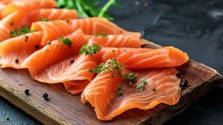 Mehrere Lachsscheiben liegen auf einem Holzbrett.