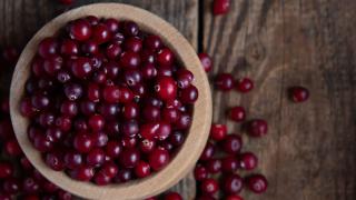 Eine Schüssel mit Preiselbeeren steht auf einem Holztisch.