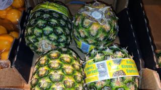 Vier Ananas ohne Krone liegen in einer Obstkiste.