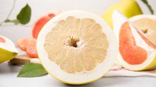 Halbierte Pomelos liegen auf einem weißen Tisch.