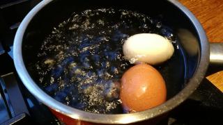 Ein Topf mit kochendem Wasser und zwei Eiern